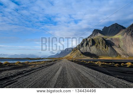 Road mountain and black volcanic lava sand dunes by the sea of Stokksness Southeast Iceland