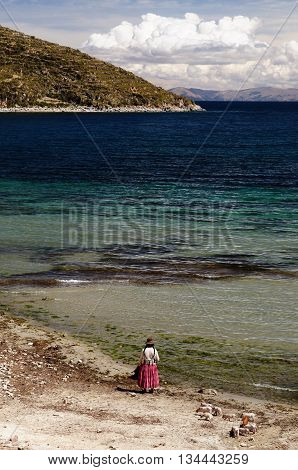 South America Bolivia - Isla del Sol on the Titicaca lake the largest highaltitude lake in the world. Woman standing in the traditional dress on the lake Titicaca