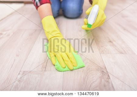 Female hands in yellow gloves wipe the floor rag.