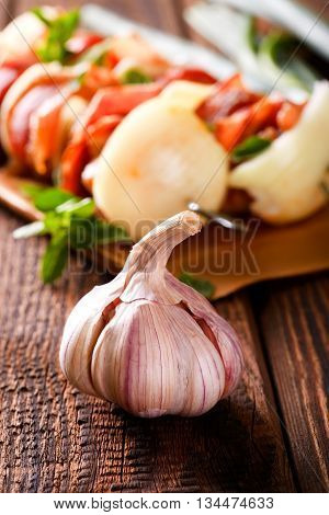 Garlic Bud On Old Wooden Board In Front Of Skewers