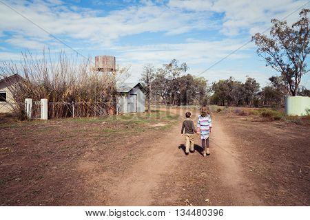 Brother and sister walking down a dirt track in outback Australia