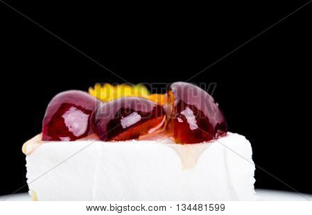 Creamy yougurt mousse cake with fruits on top. Macro against black background. Photo can be used as a whole background.
