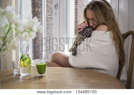 Pretty blonde cuddling her cat in the morning