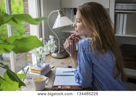 Attractive lady drinking morning coffee in her home office