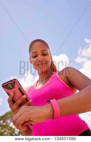 Young people doing sport activities woman runner jogging programming fit watch and synchronizing data with mobile phone wirelessly