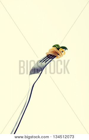 Pasta on fork tines, garnished with basil leaf