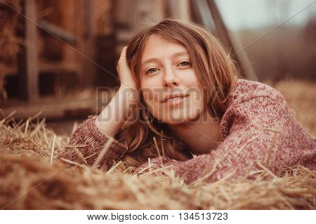 Cute country girl relaxed lying in hay.