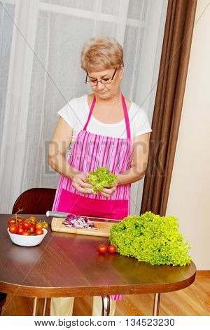 Senior woman tearing green lettuce