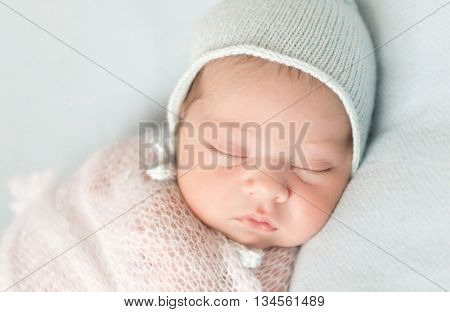 beautiful sleeping newborn baby in hat and wrapped close-up
