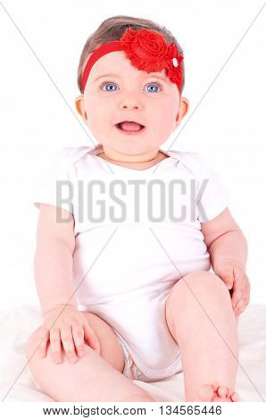 Baby girl with red ribbon on white sofa.