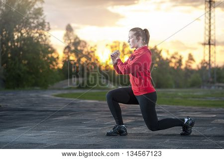 Fit woman in sportswear doing frontal lunges (squats). Fitness workout sport outdoors concept.
