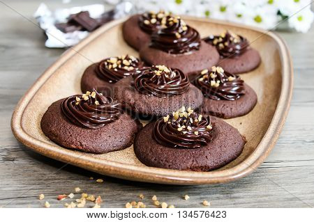 Chocolate cookies with ganache cream and hazelnut on wooden table