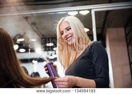 Close-up portrait of a hairdresser with hair spray fixating client hairdo at salon