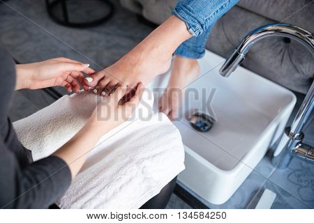 Close-up portrait of a pedicurist hands doing nails to a client at the salon