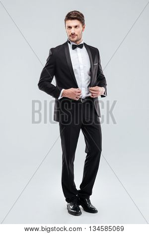 Full length of handsome young man in tuxedo with bowtie standing