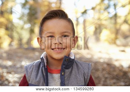 Head and shoulders portrait of a Hispanic boy in a forest