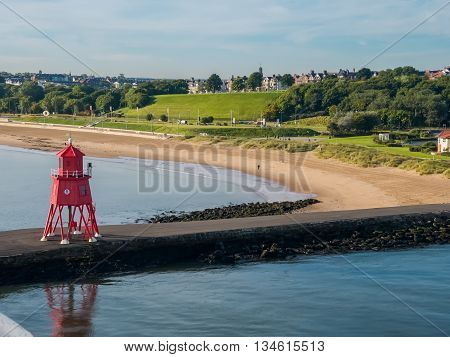 Red-colored lighthouse at The Port of Tyne at North Shields Harbor of Newcastle, England as seen from a ferry ship