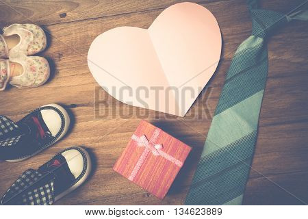 Daddy's boots baby's shoes Textile hearts gift and blue necktie on wooden background .fathers day concept vintage color