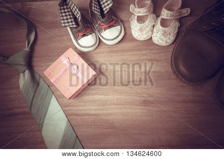 Daddy's boots baby's shoes Textile hearts gift and blue necktie on wooden background .fathers day concept vintage color