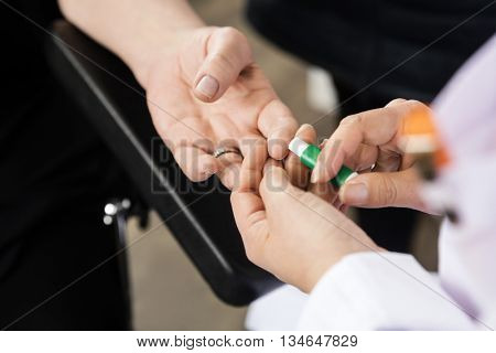 Doctor Using Tool On Patient's Finger For Blood Test In Hospital
