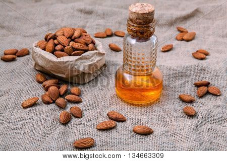 Bottle Of Extra Virgin Almonds Oil With Whole Almonds On Hempsack Background.