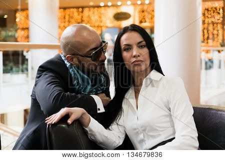 Arab man and stylish girl sit on a sofa in shopping centre