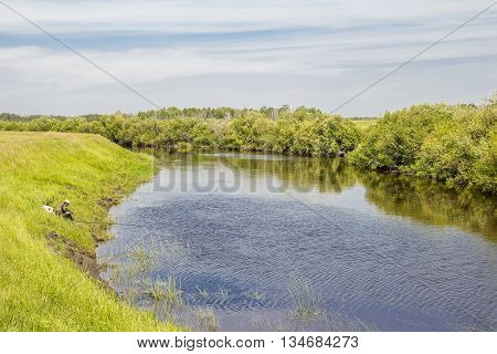 The river Kargat Novosibirsk oblast Siberia Russia - June 12 2016: a fisherman catches a fish on the river on a float