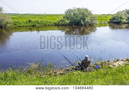 The river Kargat Novosibirsk oblast Siberia Russia - June 12 2016: a fisherman catches a fish on the river on a float