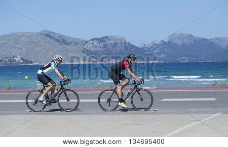 Mallorca Spain - May 4 2016: Cyclist passes a typical beach on the boardwalk at Alcudia Beach.