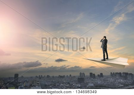 business man on paper plane flying above urban scene spying shot by binocular lens business conception concept