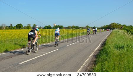 Grafham, Cambridgeshire, England - May 22, 2016:  Triathletes on cycling stage racing on public road, moving away.