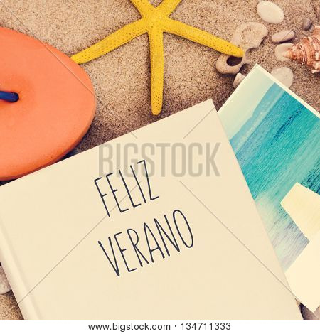 high-angle shot of a book with the text feliz verano, happy summer in Spanish written in its cover, an orange flip-flop, a starfish and a picture of the sea taken by myself, on the sand of a beach