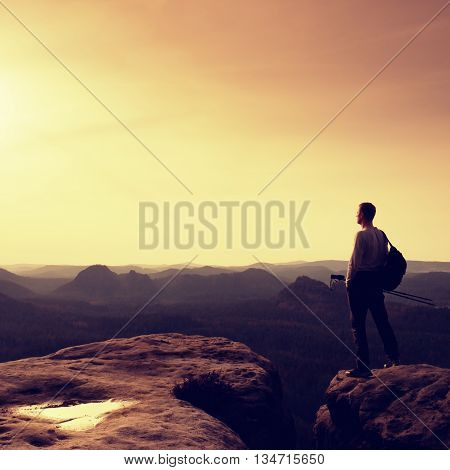Tourist On Cliff Edge With Pole In Hand And Backpack