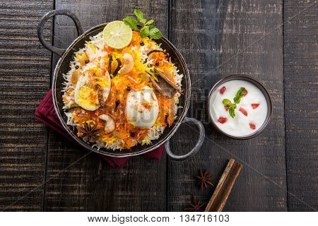 Basmati rice slowly cooked with Masala roasted egg and spices served in kadhai or kadai with yogurt dip, selective focus, egg biryani or anda rice or egg rice