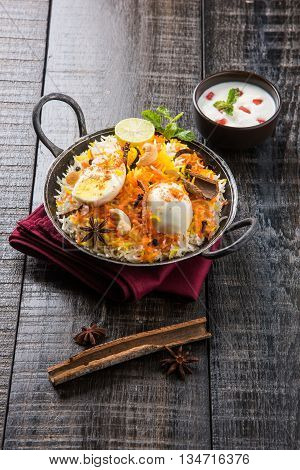Basmati rice slowly cooked with Masala roasted egg and spices served in kadhai or kadai with yogurt dip, selective focus, egg biryani or anda rice or egg rice