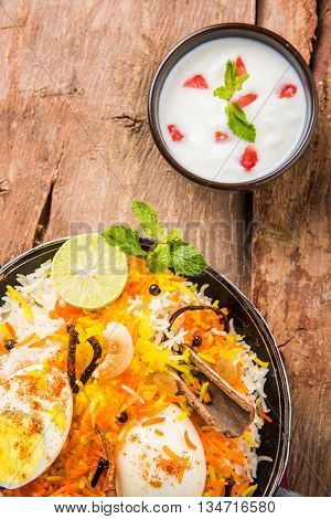 Basmati rice slowly cooked with Masala roasted egg and spices served in kadhai or kadai with yogurt dip, selective focus, egg biryani or anda rice or egg rice