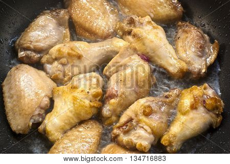 Cooking fried chicken wings in a pan