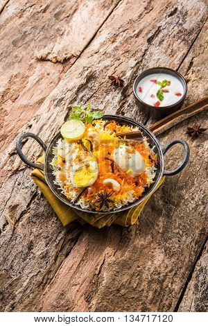 Basmati rice slowly cooked with Masala roasted egg and spices served in kadhai or kadai with yogurt dip, selective focus, egg biryani or anda rice or egg rice