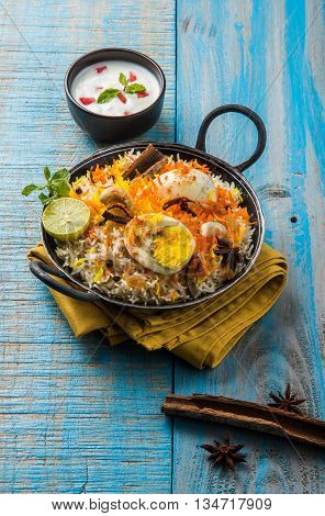Basmati rice slowly cooked with Masala roasted egg and spices served in kadhai or kadai with yogurt dip, selective focus, egg biryani or anda rice or egg rice