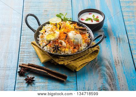 Basmati rice slowly cooked with Masala roasted egg and spices served in kadhai or kadai with yogurt dip, selective focus, egg biryani or anda rice or egg rice