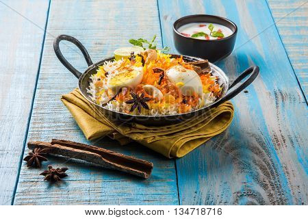 Basmati rice slowly cooked with Masala roasted egg and spices served in kadhai or kadai with yogurt dip, selective focus, egg biryani or anda rice or egg rice