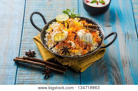Basmati rice slowly cooked with Masala roasted egg and spices served in kadhai or kadai with yogurt dip, selective focus, egg biryani or anda rice or egg rice