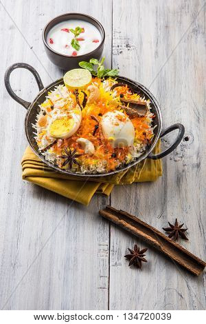 Basmati rice slowly cooked with Masala roasted egg and spices served in kadhai or kadai with yogurt dip, selective focus, egg biryani or anda rice or egg rice