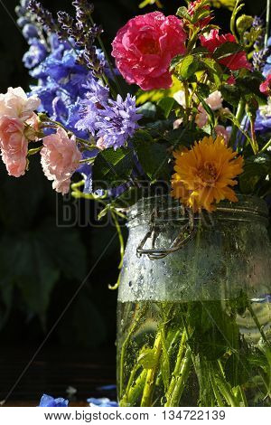 Sun after rain - colorful flowers bouquet in the garden with roses lavendel grape leaves and blue delfinium