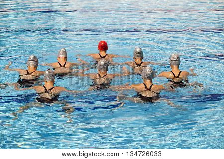 Synchronized swimming team performing a synchronized routine of elaborate moves in the water