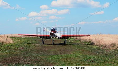 Old plane with a propeller on the runway on a background of blue sky
