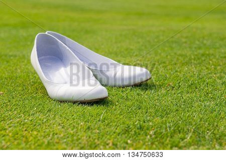 particular of white wedding shoes on grass