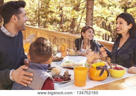 Happy family eating at table on a deck in a forest