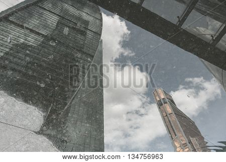 Reflection of skyscrapers in puddle on the pavement