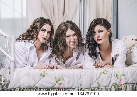 Three Beautiful Young Women Friends Chatting In The Bedroom In  Shirts